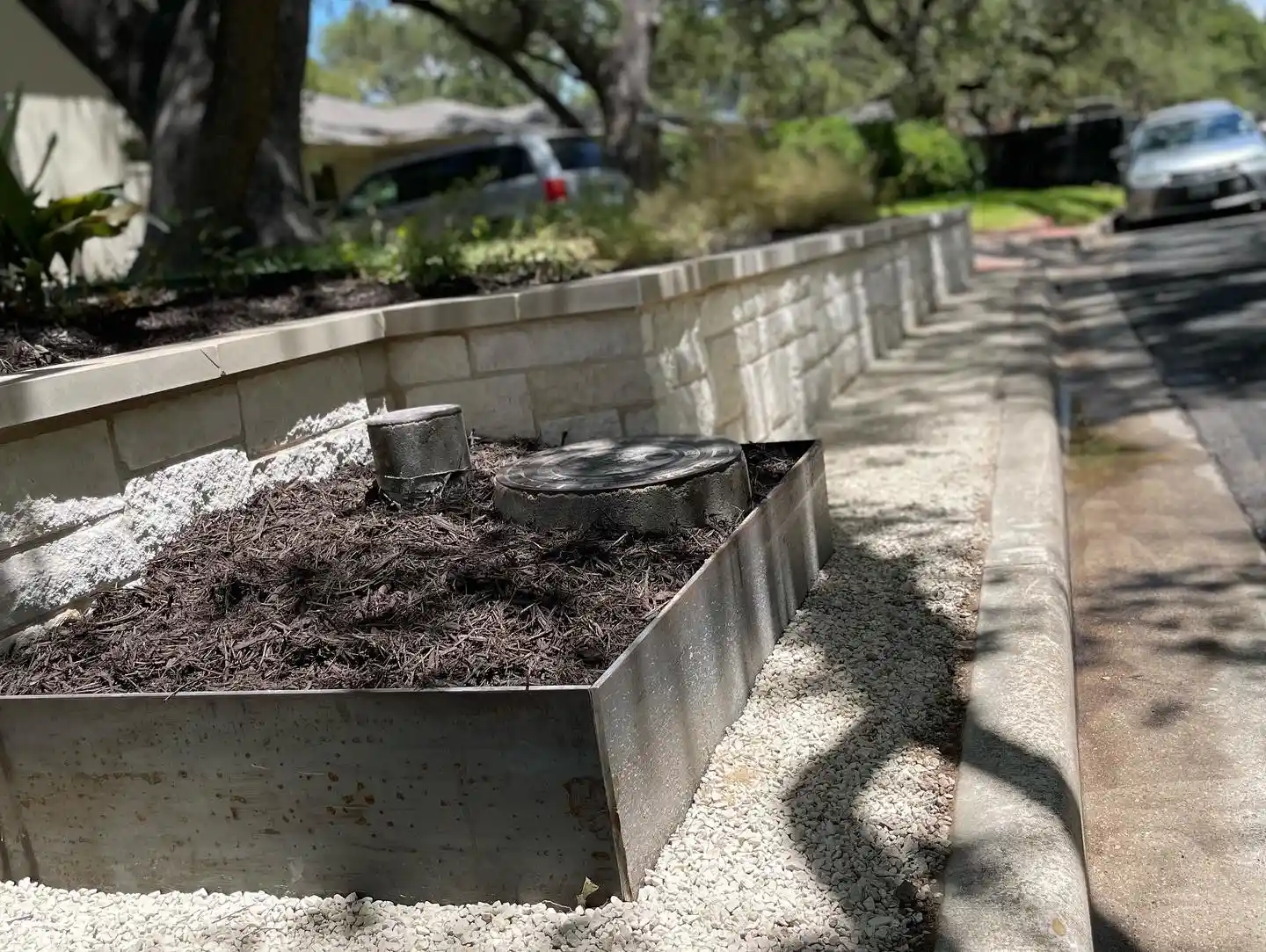 Limestone block retaining wall with steel planter edging along a residential Austin street