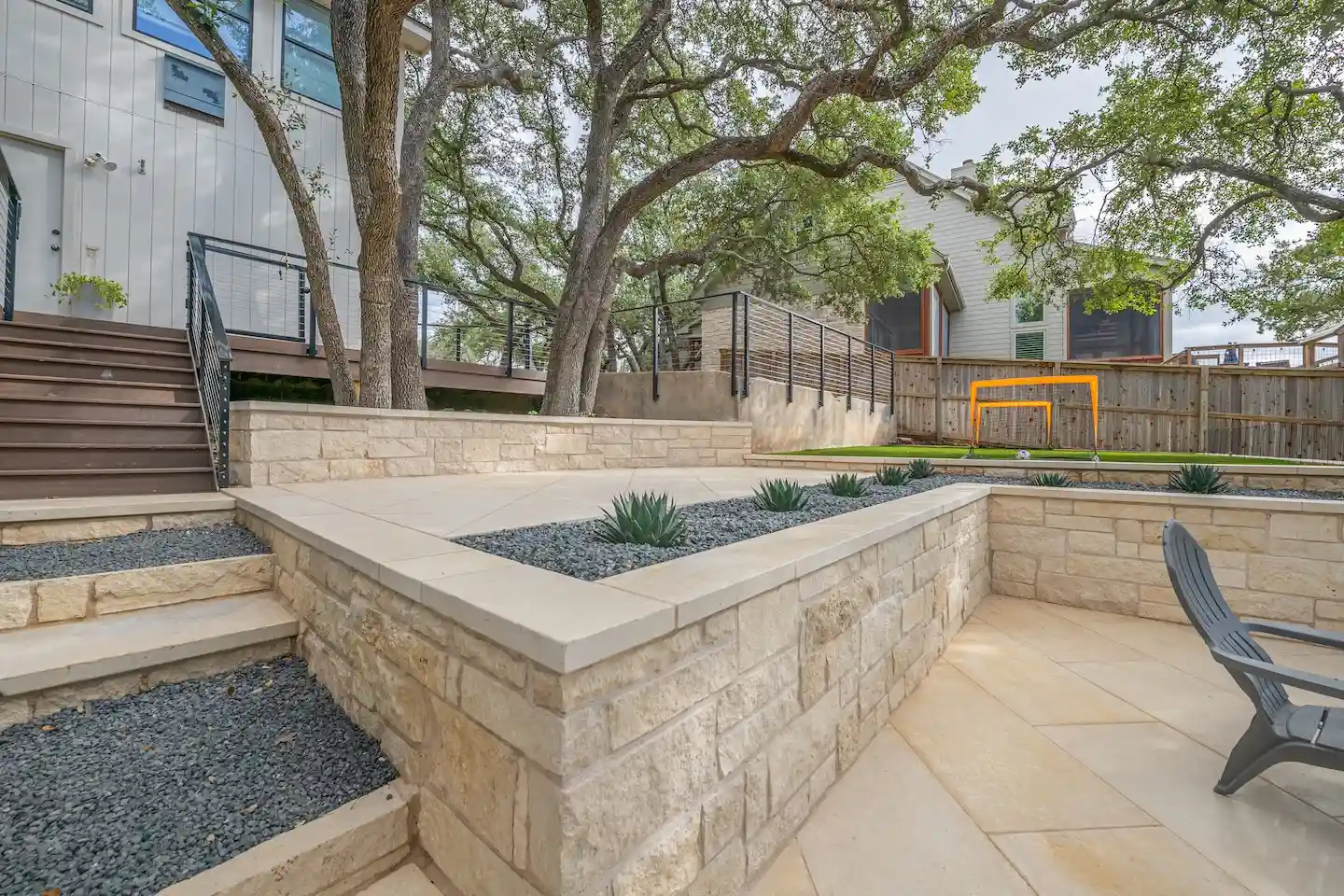 Finished limestone block retaining wall with cut-stone cap enclosing a backyard patio in Austin, Texas