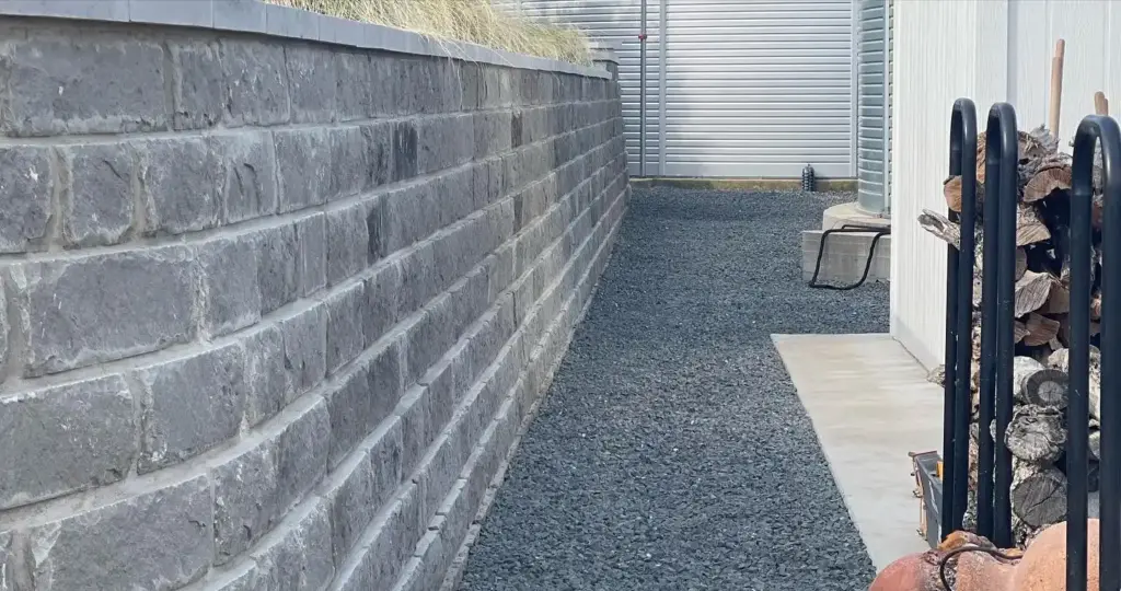 Hardscape 10 Outdoor Living Space Ideas Worth Stealing for Your Austin Backyard 5 Curved stone retaining wall creating a level, usable side yard path on a sloped Austin property.
