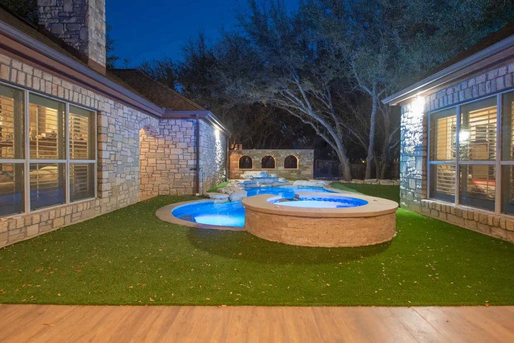 Raised stone spa wall and pool deck in a residential backyard