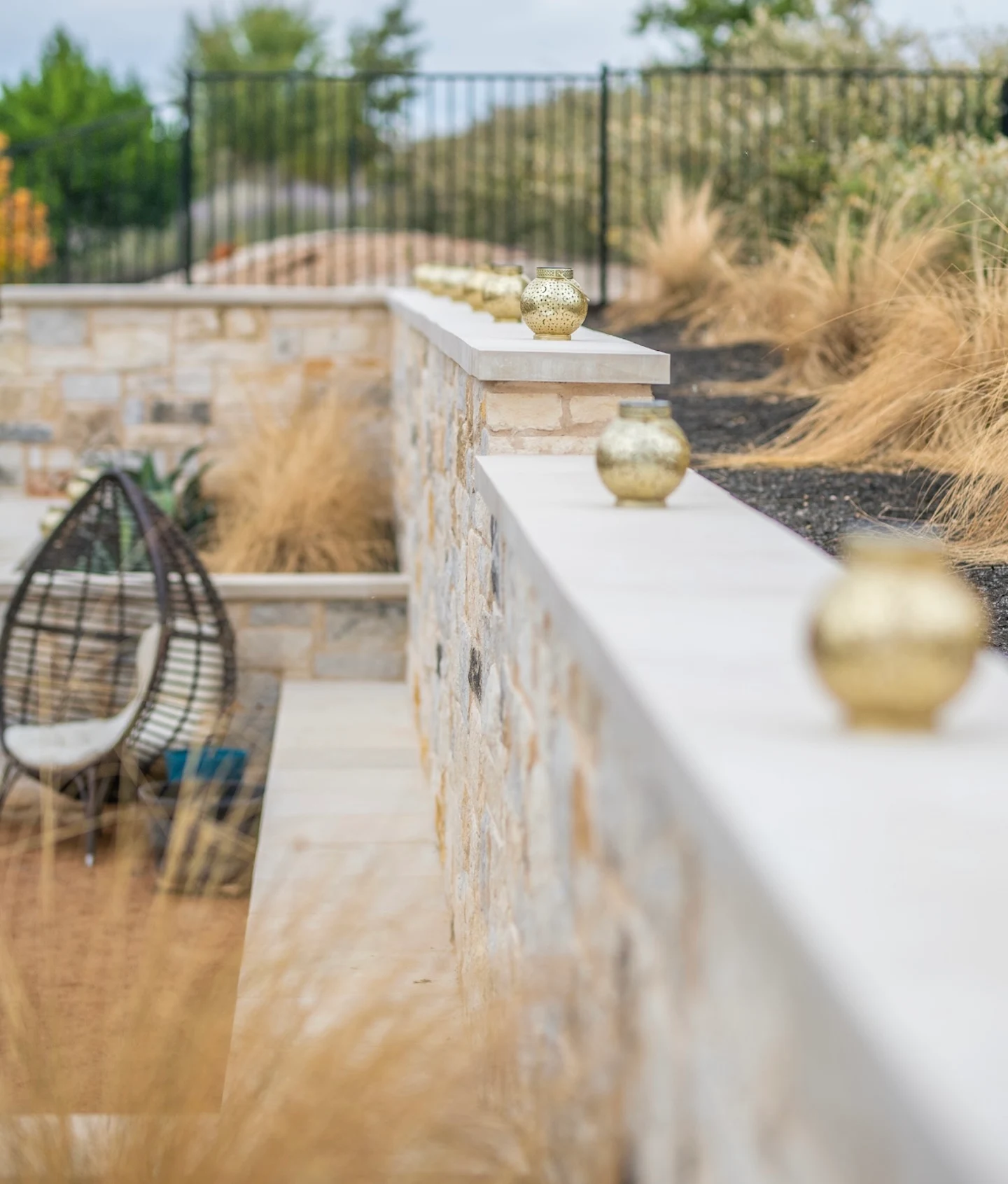 Stone seat wall separating a paved area from ornamental grass plantings 
