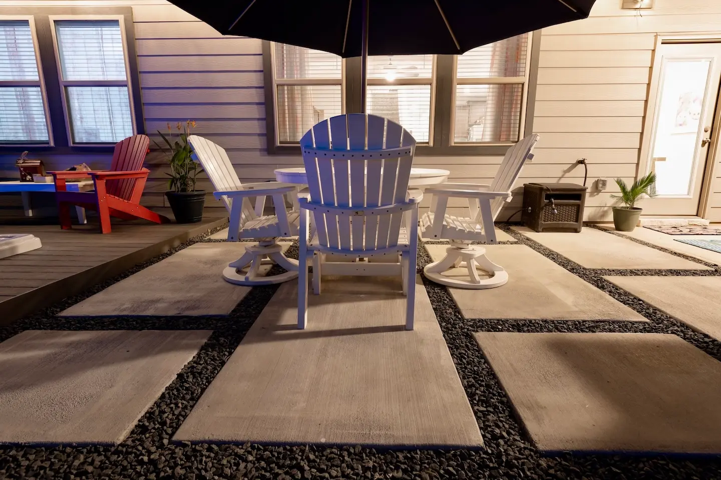 Concrete paver patio with black gravel joints and white patio dining set in a Central Texas backyard