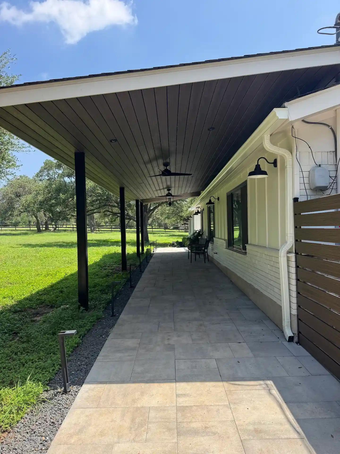 Attached patio cover extending home's roofline over paver walkway in Austin